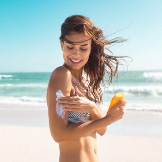 Sieviete uzklāj SPF 50 saules aizsargkrēmu pludmalē